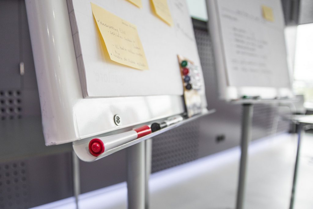 Bottom of a whiteboard, showing sticky notes and a tray of whiteboard markers