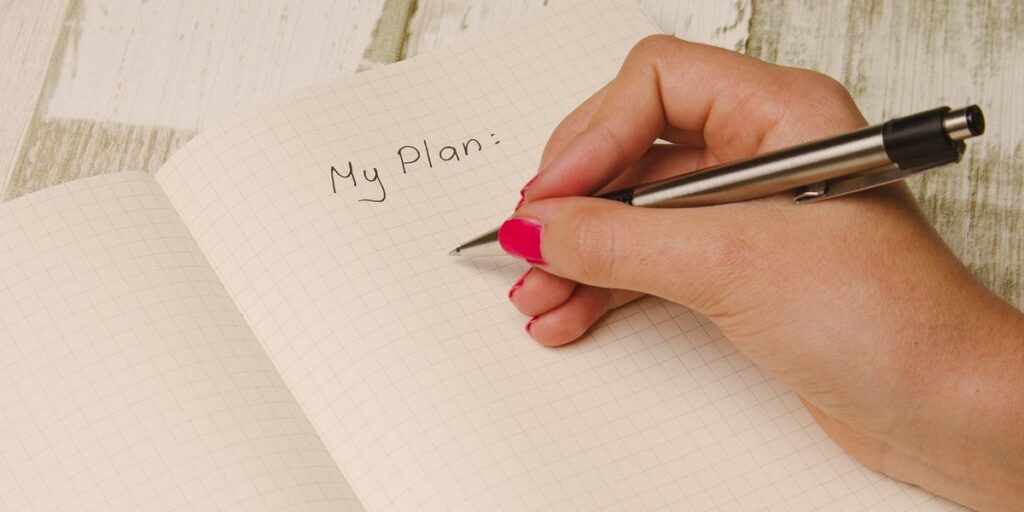 Researcher writing "My Plan" into a paper notebook