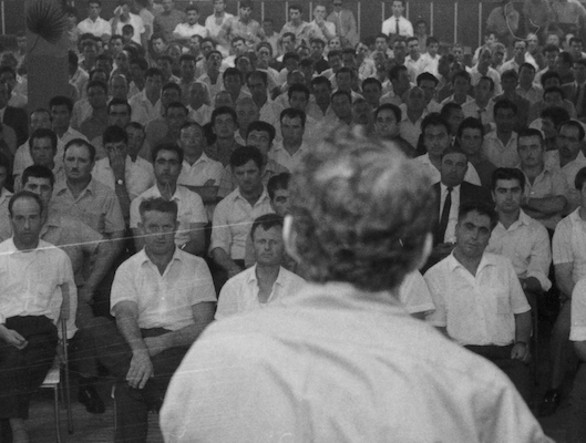 Image of man giving a speech in front of a seated audience