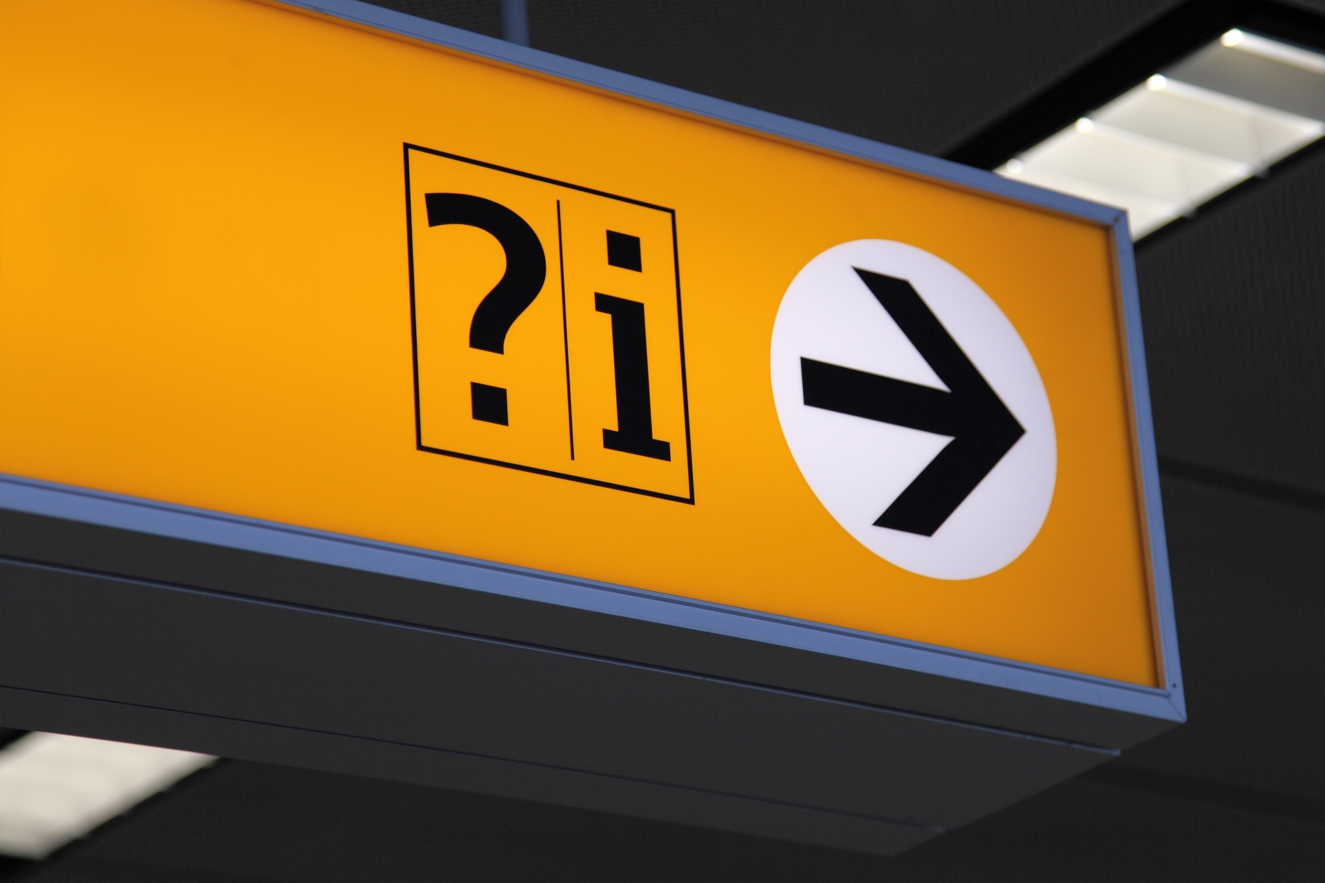 A yellow information sign with a question mark icon, an 'i' icon, and an arrow pointing to the right.